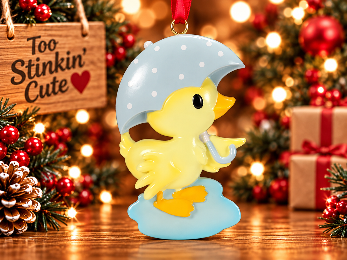 Yellow ducky personalized ornament hanging on a Christmas tree with warm holiday lights and greenery