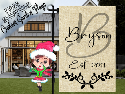 Burlap-look garden flag with a sage B monogram, Bryson name, establishment year and black leafy flourish in front of a porch.