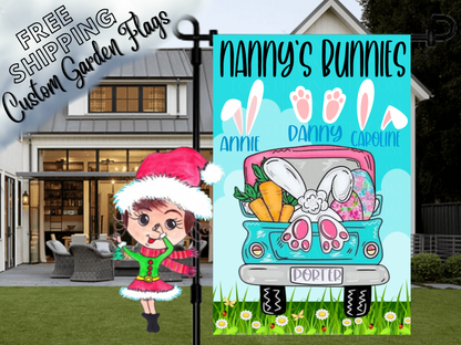 Nanny's Bunnies garden flag with named bunny-ear and paw motifs above a turquoise truck on blue in front of a porch.