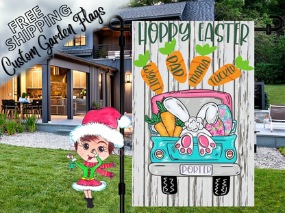 White wood-print Easter garden flag with turquoise truck, bunny feet and named carrots, shown outside a house at dusk.