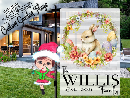 Gray striped Willis family garden flag with a bunny, pastel eggs and spring flowers, shown outside a house.