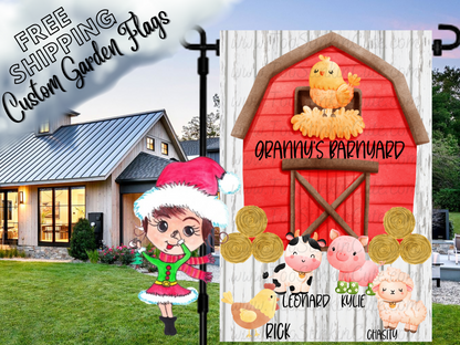 Granny’s Barnyard garden flag with a red barn, named farm animals, yellow chick and hay bales on a white wood-print background. Shown beside a white house.
