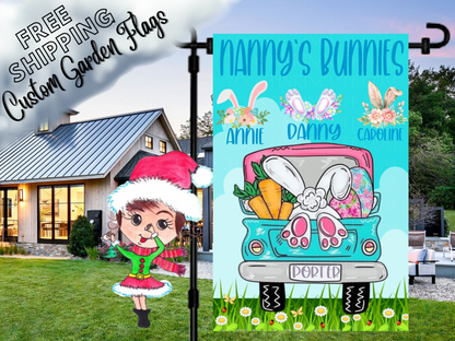 Nanny's Bunnies garden flag with floral bunny-ear motifs, names and a turquoise Easter truck beside a white house.