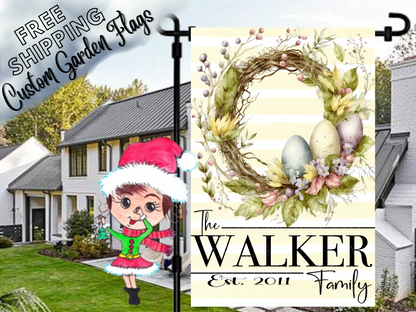 Walker family garden flag with pastel Easter eggs, a twig-and-foliage wreath and pale yellow stripes in a daytime yard.