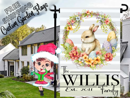 Willis family garden flag with a brown bunny, pastel Easter eggs and floral wreath, displayed in a daytime yard.