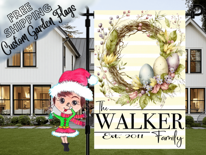 Walker family garden flag with pastel Easter eggs, a twig-and-foliage wreath and pale yellow stripes in front of a porch.