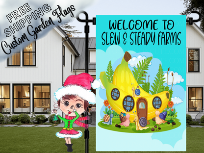 Slow and Steady Farms welcome flag with a yellow cottage, snails and flowers, displayed in front of a porch.