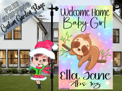 Welcome Home Baby Girl garden flag with a sloth, rainbow background, Ella Jane example name and birth details in a close garden-stand view.