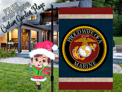 Proud Wife of a Marine garden flag with a Marine Corps eagle, globe and anchor emblem, navy background and red and cream bands. Shown outside a house.