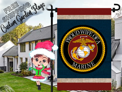 Proud Wife of a Marine garden flag with a Marine Corps eagle, globe and anchor emblem, navy background and red and cream bands. Shown beside a white house.