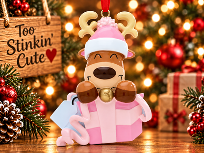 Front view of reindeer peeking out of a pink present with pale pink ribbon and curled bow details.