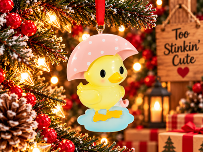 Front view of yellow duck Christmas ornament standing on a blue puddle beneath a pink umbrella.