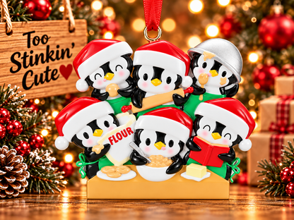 Penguin baking family of six ornament displayed beside a Too Stinkin’ Cute wooden sign in a rustic Christmas setting.