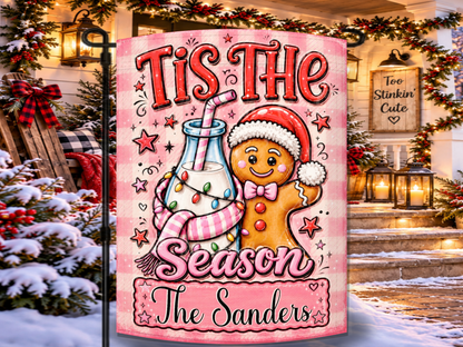 Personalized ’Tis the Season Christmas garden flag featuring a smiling gingerbread character, milk bottle, pink striped straw, Christmas lights, and custom family name.