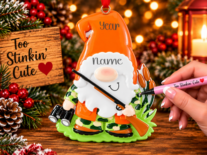 Personalized hunting gnome Christmas ornament wearing an orange hat and camouflage outfit, with a white beard and cheerful smile.