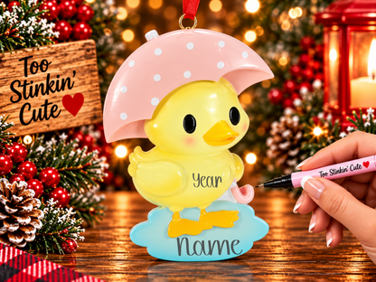 Close-up of yellow duck ornament with rosy cheeks, orange beak, and pink umbrella with white polka dots.