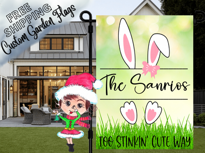 Green garden flag mockup with white bunny ears and feet, a pink bow, grass and family name.