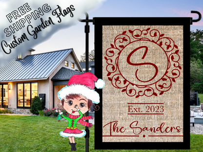 Burlap-look garden flag mockup with a red S monogram, ornate circular frame, establishment year and Sanders family name.