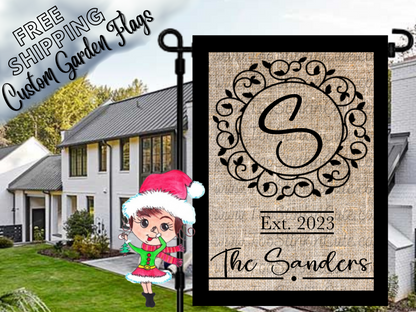 Burlap-look garden flag mockup with a black S monogram, ornate circular frame, establishment year and Sanders family name.