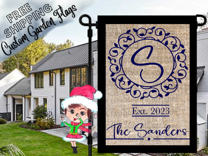 Burlap-look garden flag mockup with a blue S monogram, ornate circular frame, establishment year and Sanders family name.