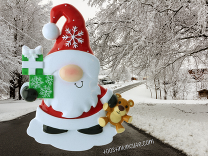 Unlettered Christmas gnome ornament with a red hat, white beard, green present, and teddy bear.