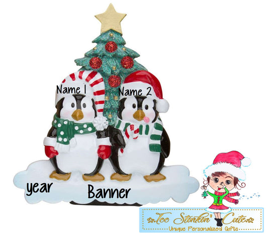 Family of 2 table topper with penguins in winter hats beside a decorated Christmas tree. Sample personalization labels are shown.